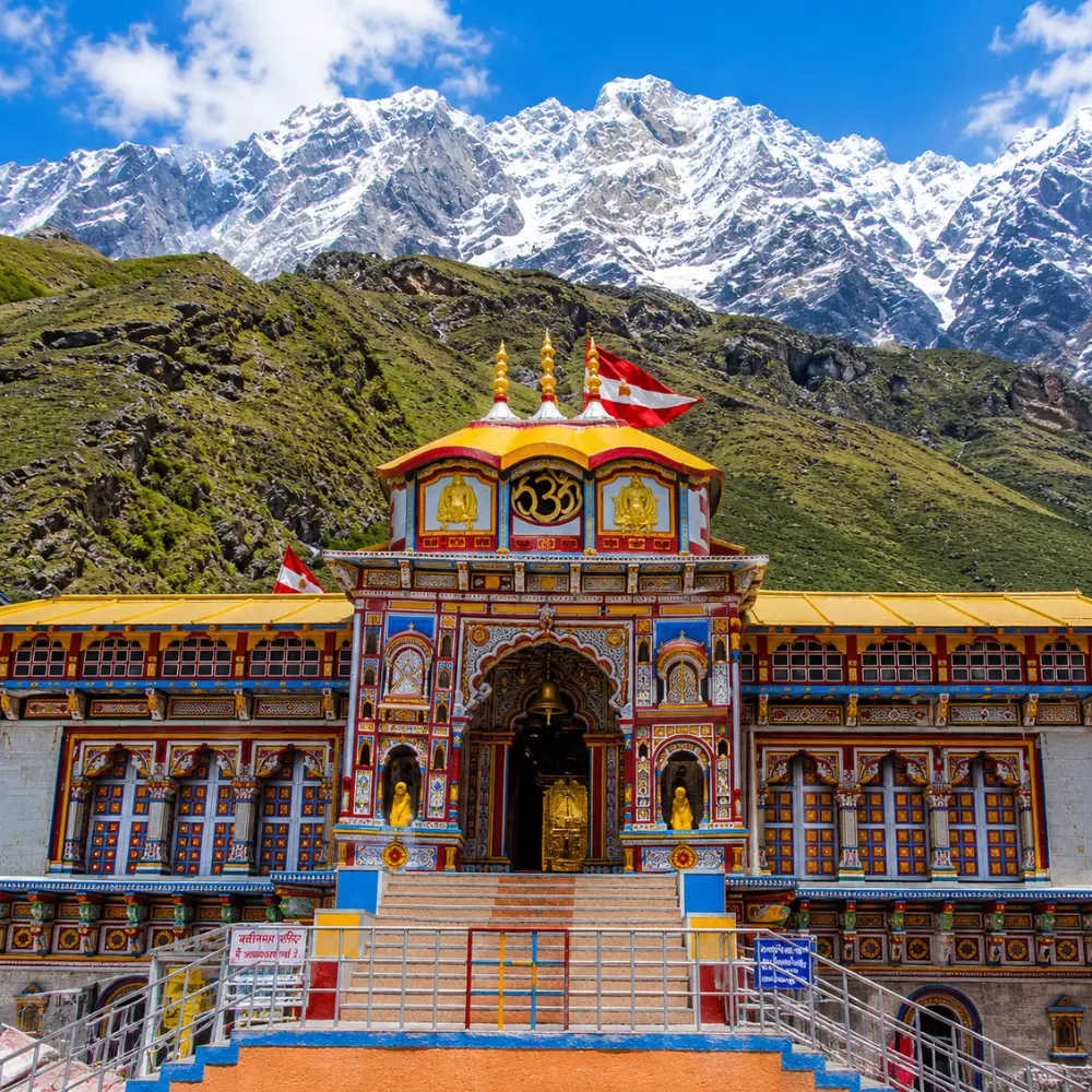 Bright morning view of Badrinath Temple with colorful facade, Himalayan mountains, and clear sacred valley scenery