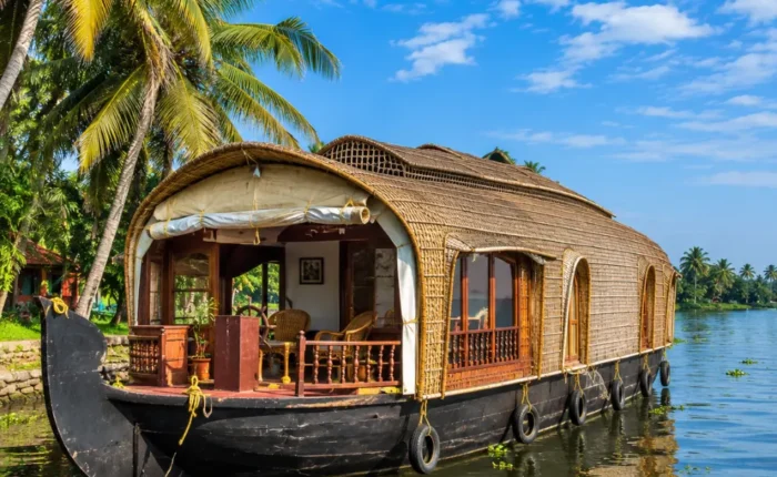 Alleppey houseboat floating on peaceful Kerala backwaters with coconut palms and clear morning daylight.