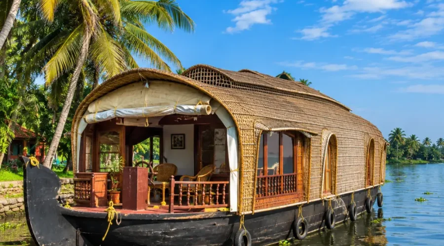 Alleppey houseboat floating on peaceful Kerala backwaters with coconut palms and clear morning daylight.