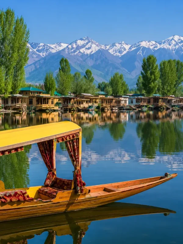 Beautiful Srinagar Dal Lake view with colorful shikara, houseboats, calm water reflections, and snow-capped mountains.