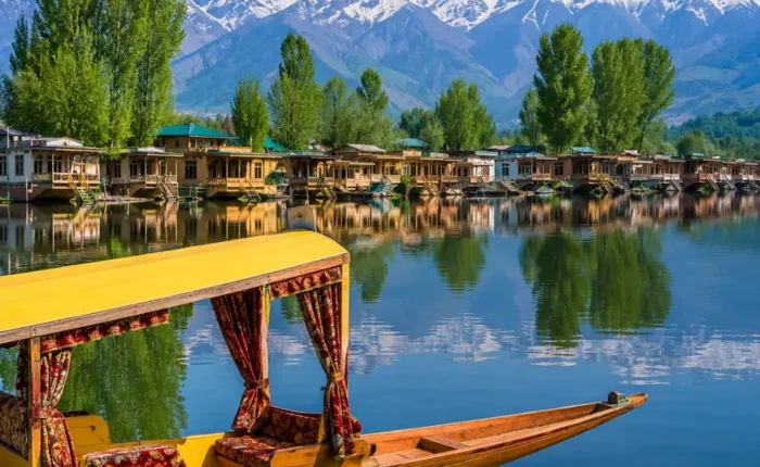 Beautiful Srinagar Dal Lake view with colorful shikara, houseboats, calm water reflections, and snow-capped mountains.