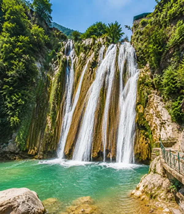 Bright morning view of Kempty Falls in Mussoorie with clear cascading water, rocky cliffs, and lush green hills
