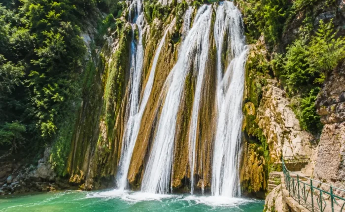 Bright morning view of Kempty Falls in Mussoorie with clear cascading water, rocky cliffs, and lush green hills