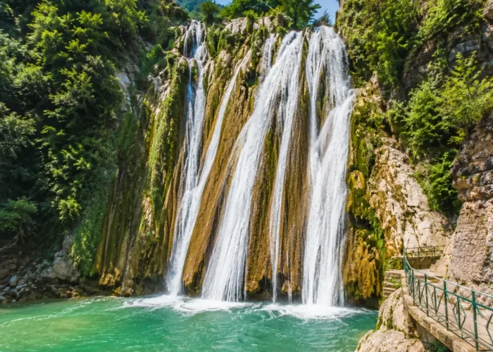 Bright morning view of Kempty Falls in Mussoorie with clear cascading water, rocky cliffs, and lush green hills