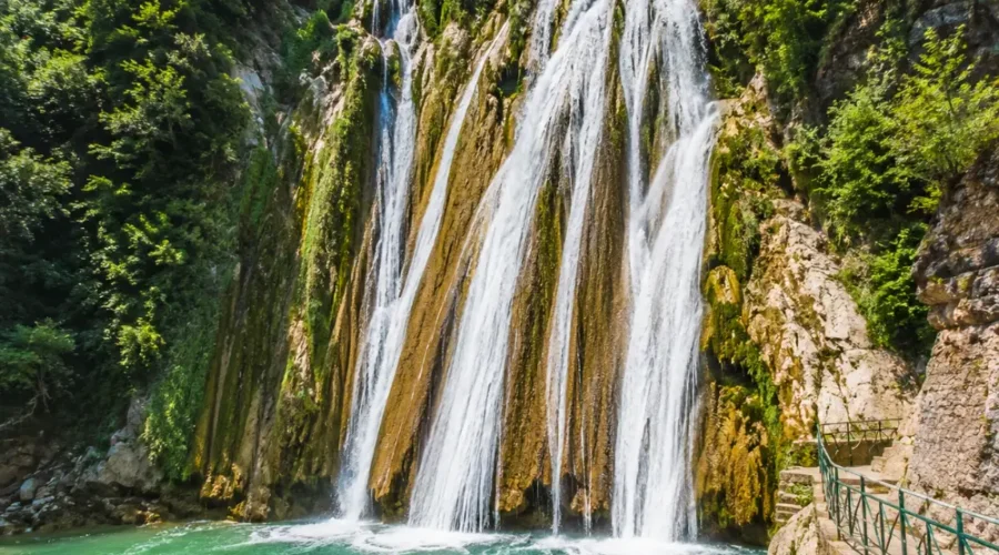 Bright morning view of Kempty Falls in Mussoorie with clear cascading water, rocky cliffs, and lush green hills