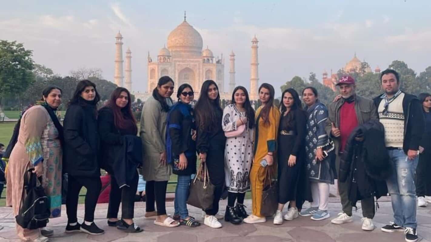 Women tourists posing in front of red sandstone architecture in India, traditional ethnic dresses, sightseeing, cultural tourism, India travel destination, group travel, India Tours & Travels, India tourism, heritage site exploration.