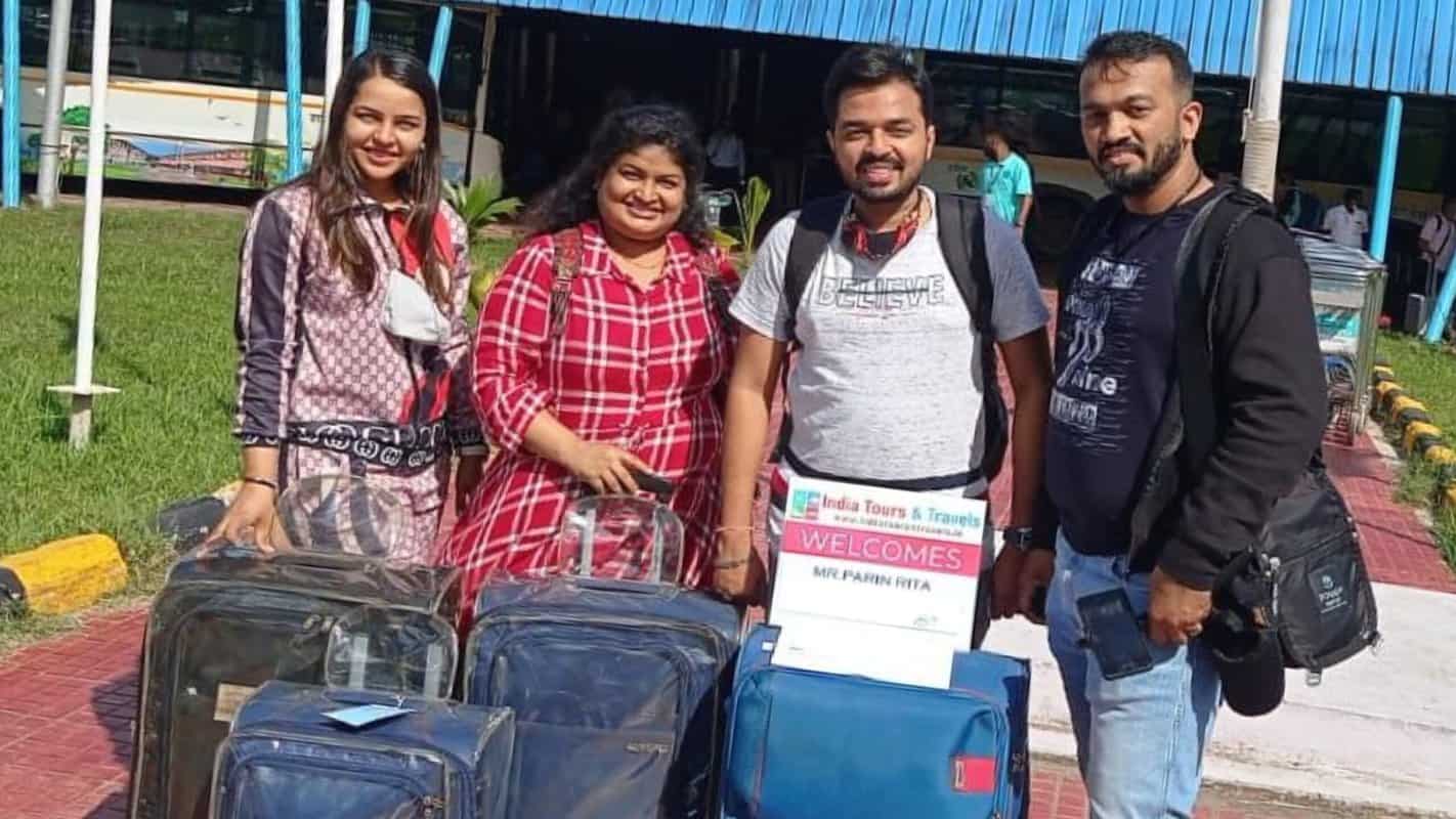 Luggage collection at India Tours & Travels airport arrival, happy travelers with backpacks and suitcases greeting at the terminal, showcasing trusted travel services in India.
