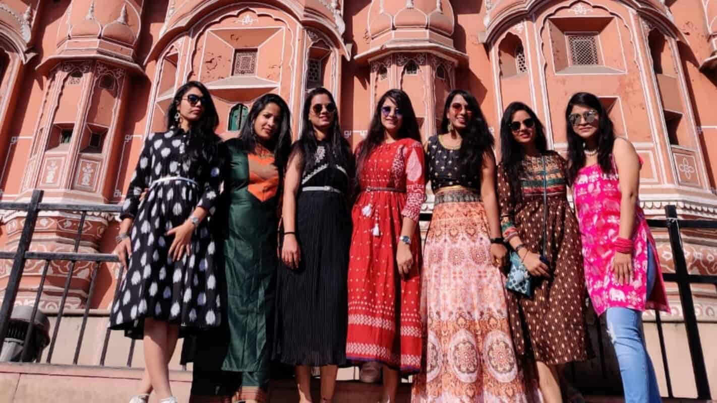 Women tourists posing in front of red sandstone architecture in India, traditional ethnic dresses, sightseeing, cultural tourism, India travel destination, group travel, India Tours & Travels, India tourism, heritage site exploration.