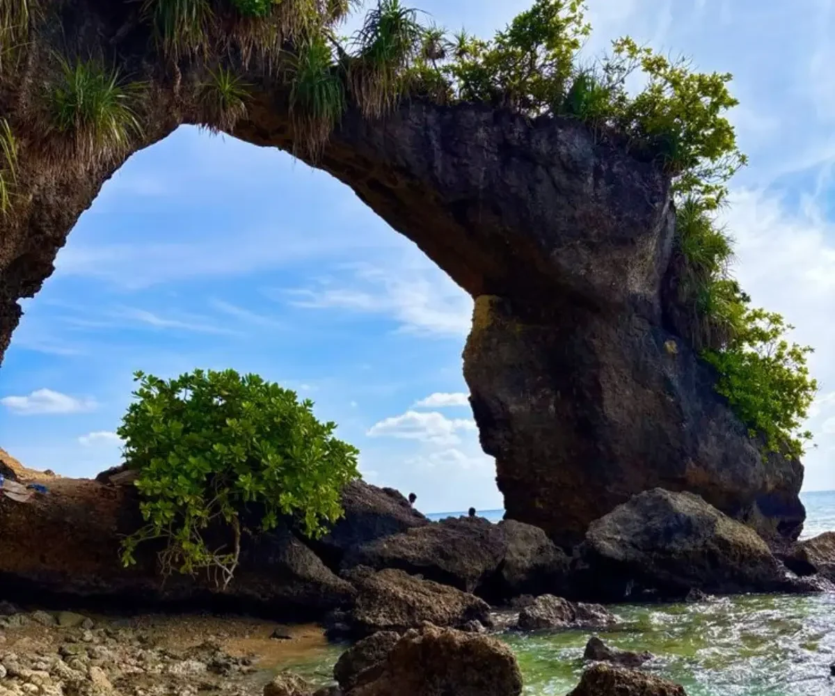 Natural rock bridge in Andaman with blue sky, sea waves, coastal rocks and tropical island scenery