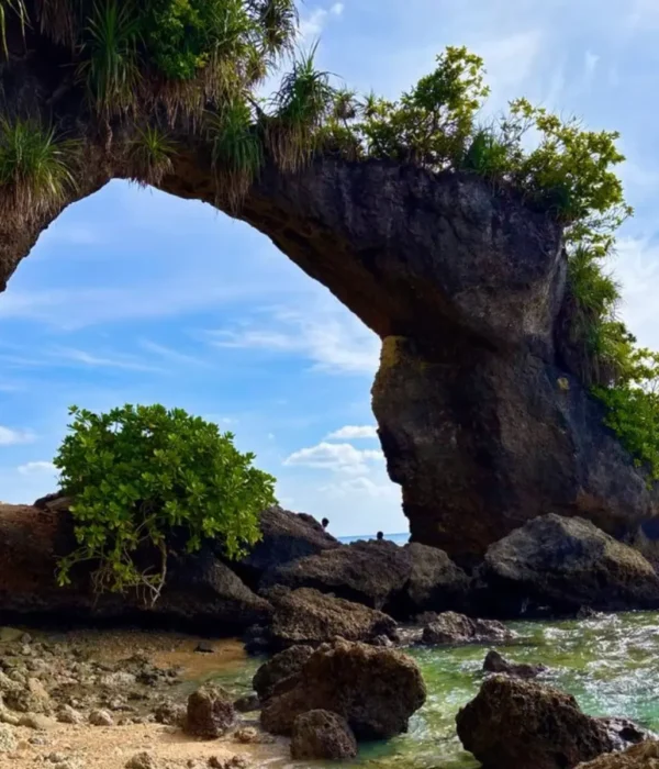 Natural rock bridge in Andaman with blue sky, sea waves, coastal rocks and tropical island scenery