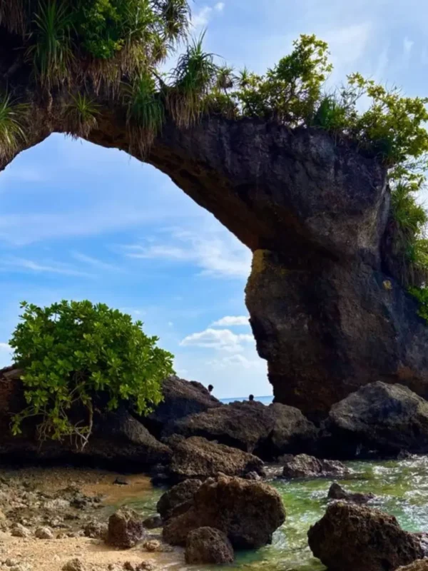 Natural rock bridge in Andaman with blue sky, sea waves, coastal rocks and tropical island scenery