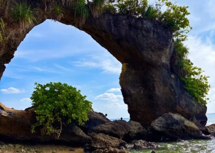 Natural rock bridge in Andaman with blue sky, sea waves, coastal rocks and tropical island scenery