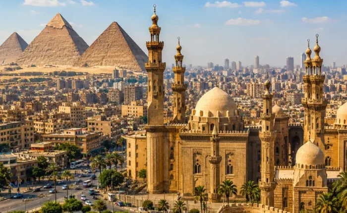 Bright daytime view of Cairo with historic mosque architecture, city skyline, palm trees, and Giza pyramids.