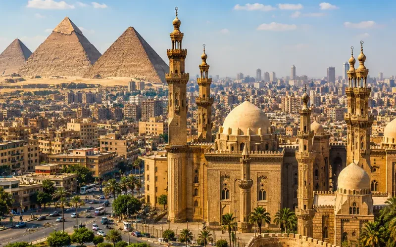 Bright daytime view of Cairo with historic mosque architecture, city skyline, palm trees, and Giza pyramids.