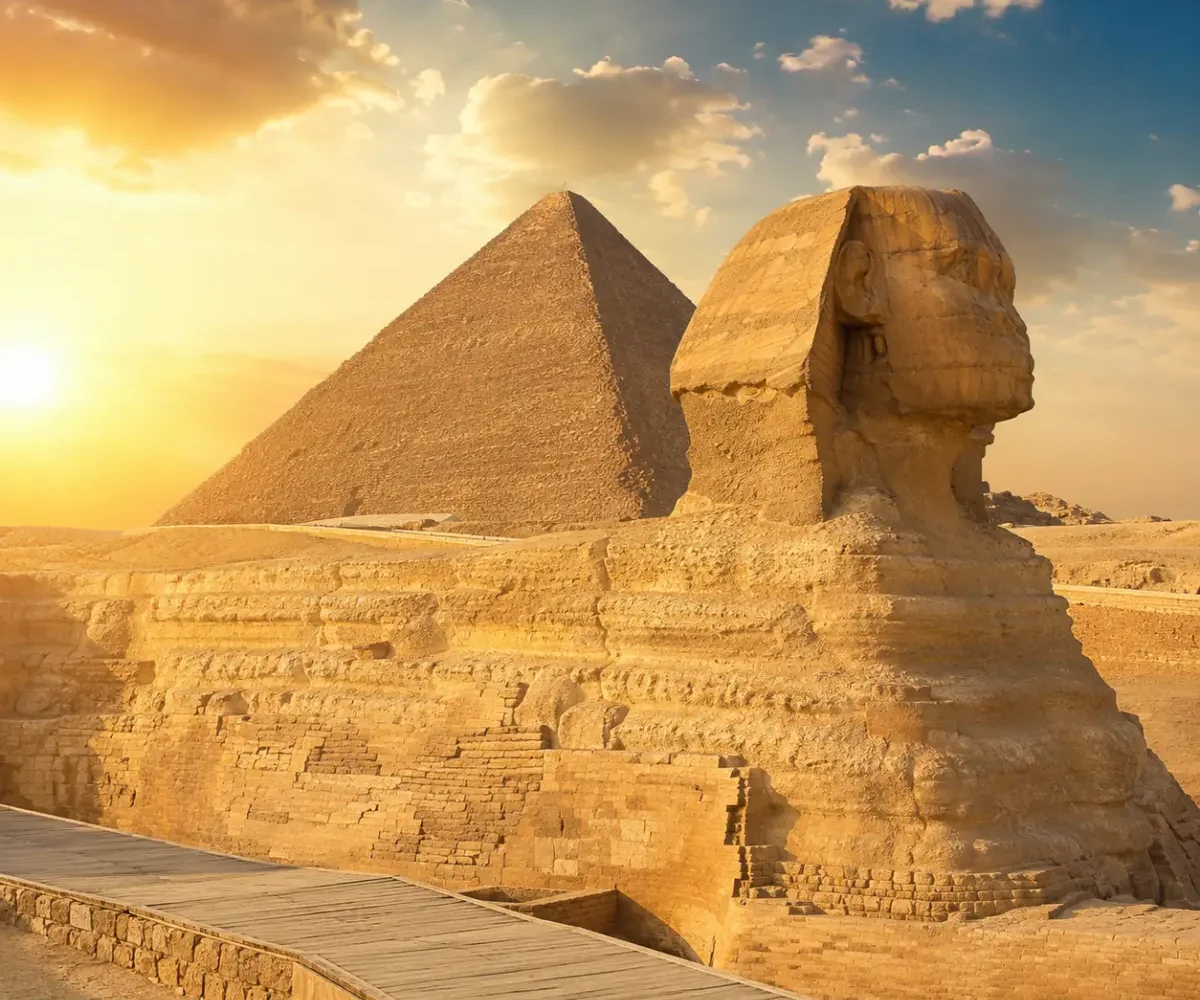 Great Sphinx of Giza with the Pyramid of Khafre in the background under warm golden light in Egypt.