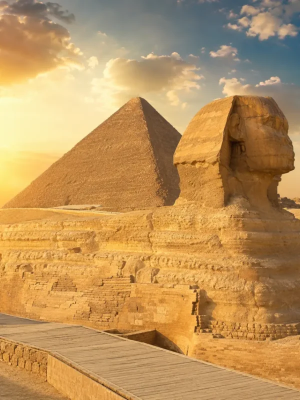Great Sphinx of Giza with the Pyramid of Khafre in the background under warm golden light in Egypt.