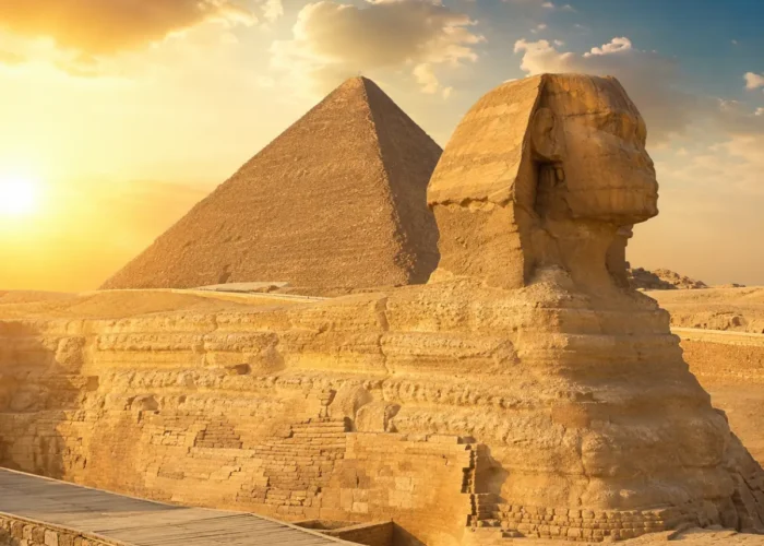 Great Sphinx of Giza with the Pyramid of Khafre in the background under warm golden light in Egypt.