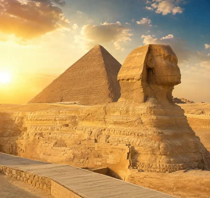 Great Sphinx of Giza with the Pyramid of Khafre in the background under warm golden light in Egypt.
