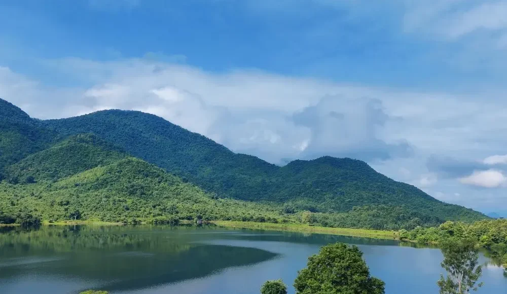 Grand Odisha Experience scenic landscape featuring a calm lake, lush green hills and peaceful natural beauty in Odisha