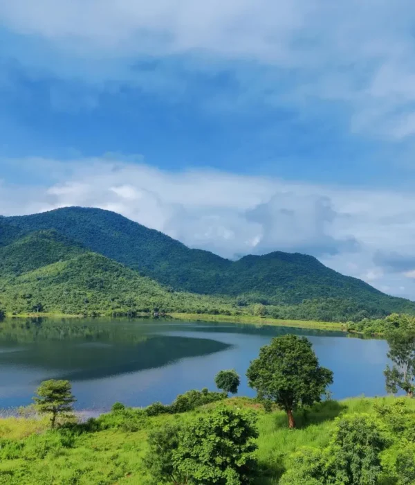 Grand Odisha Experience scenic landscape featuring a calm lake, lush green hills and peaceful natural beauty in Odisha