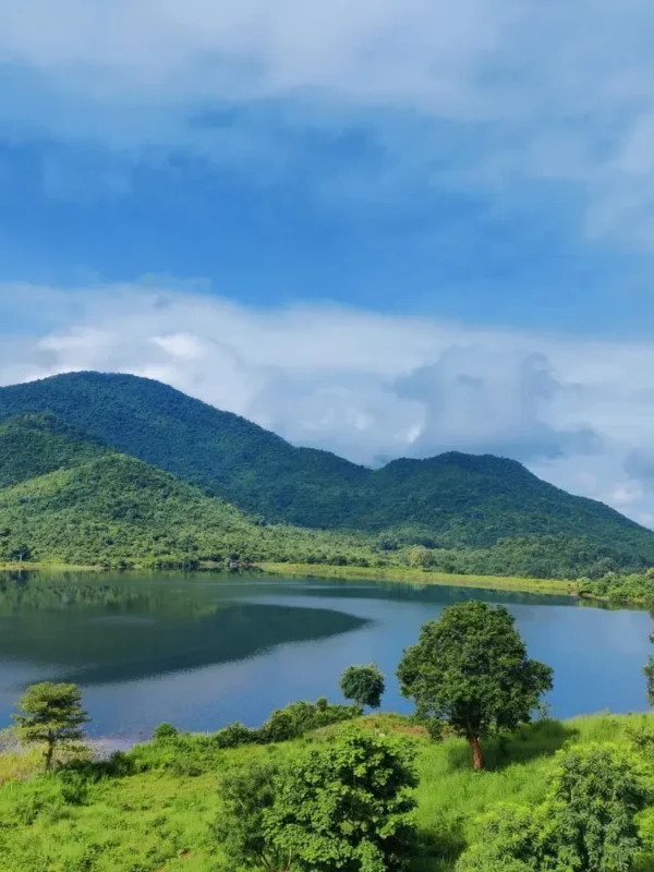 Grand Odisha Experience scenic landscape featuring a calm lake, lush green hills and peaceful natural beauty in Odisha