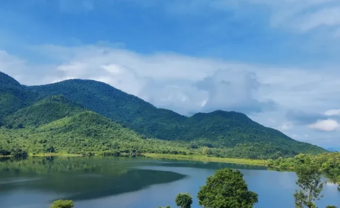 Grand Odisha Experience scenic landscape featuring a calm lake, lush green hills and peaceful natural beauty in Odisha
