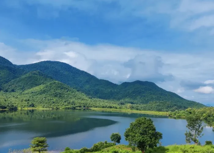 Grand Odisha Experience scenic landscape featuring a calm lake, lush green hills and peaceful natural beauty in Odisha