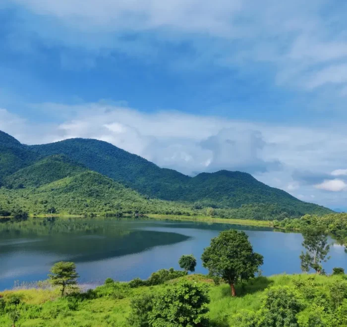 Grand Odisha Experience scenic landscape featuring a calm lake, lush green hills and peaceful natural beauty in Odisha