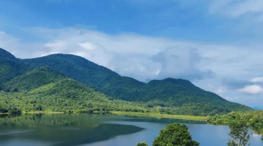Grand Odisha Experience scenic landscape featuring a calm lake, lush green hills and peaceful natural beauty in Odisha