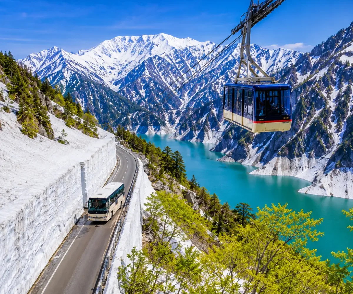 Luxury Japan Alpine Route featuring the iconic Tateyama Kurobe Snow Corridor, crystal-clear turquoise Kurobe Lake, panoramic snow-covered peaks, an alpine cable car, and a scenic mountain road under bright blue skies. No people.