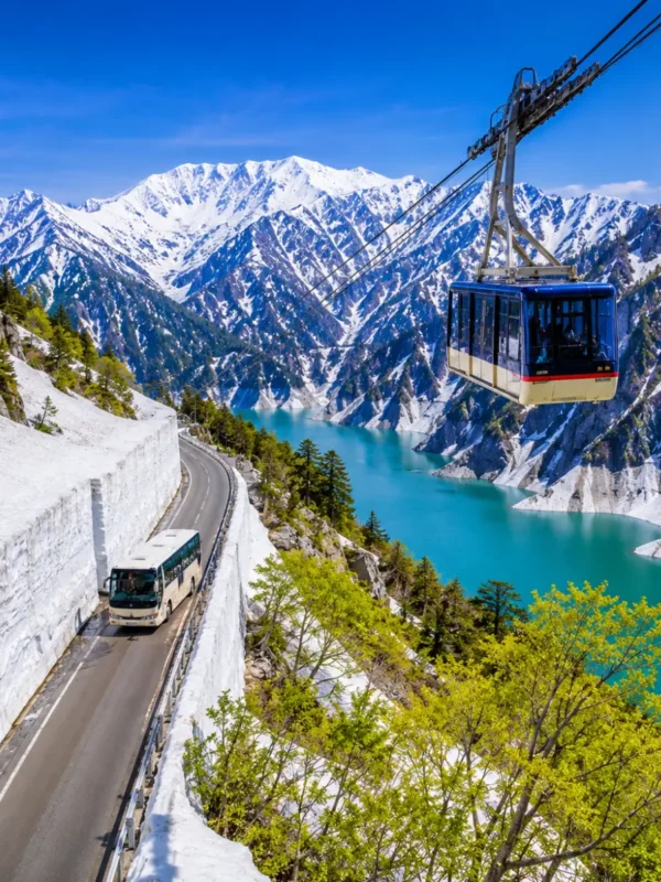Luxury Japan Alpine Route featuring the iconic Tateyama Kurobe Snow Corridor, crystal-clear turquoise Kurobe Lake, panoramic snow-covered peaks, an alpine cable car, and a scenic mountain road under bright blue skies. No people.