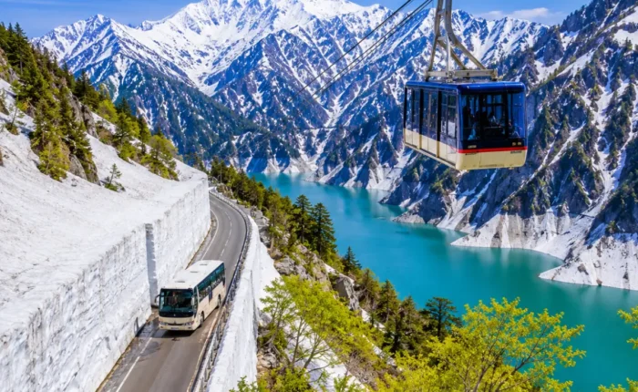 Luxury Japan Alpine Route featuring the iconic Tateyama Kurobe Snow Corridor, crystal-clear turquoise Kurobe Lake, panoramic snow-covered peaks, an alpine cable car, and a scenic mountain road under bright blue skies. No people.