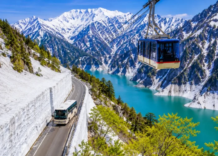 Luxury Japan Alpine Route featuring the iconic Tateyama Kurobe Snow Corridor, crystal-clear turquoise Kurobe Lake, panoramic snow-covered peaks, an alpine cable car, and a scenic mountain road under bright blue skies. No people.