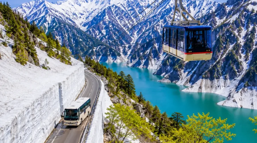 Luxury Japan Alpine Route featuring the iconic Tateyama Kurobe Snow Corridor, crystal-clear turquoise Kurobe Lake, panoramic snow-covered peaks, an alpine cable car, and a scenic mountain road under bright blue skies. No people.