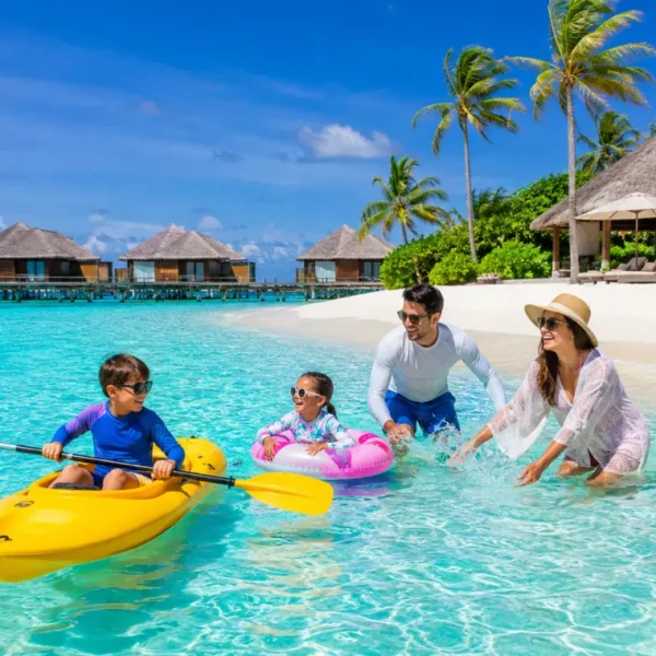 Family enjoying Maldives beach resort with turquoise lagoon, white sand, palm trees, and tropical island scenery.