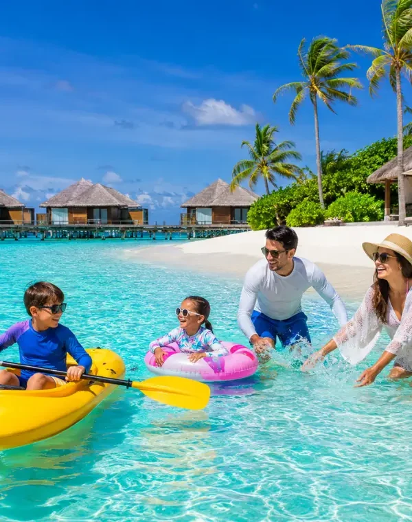 Family enjoying Maldives beach resort with turquoise lagoon, white sand, palm trees, and tropical island scenery.