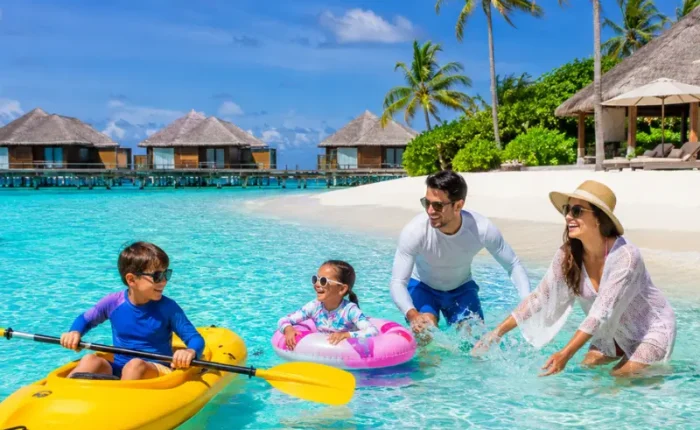 Family enjoying Maldives beach resort with turquoise lagoon, white sand, palm trees, and tropical island scenery.