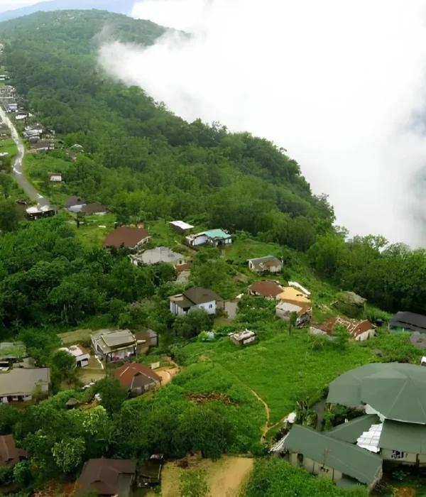 Meghalaya Explorer Package with misty hillside village, lush green forest, valley clouds and scenic Northeast India landscape