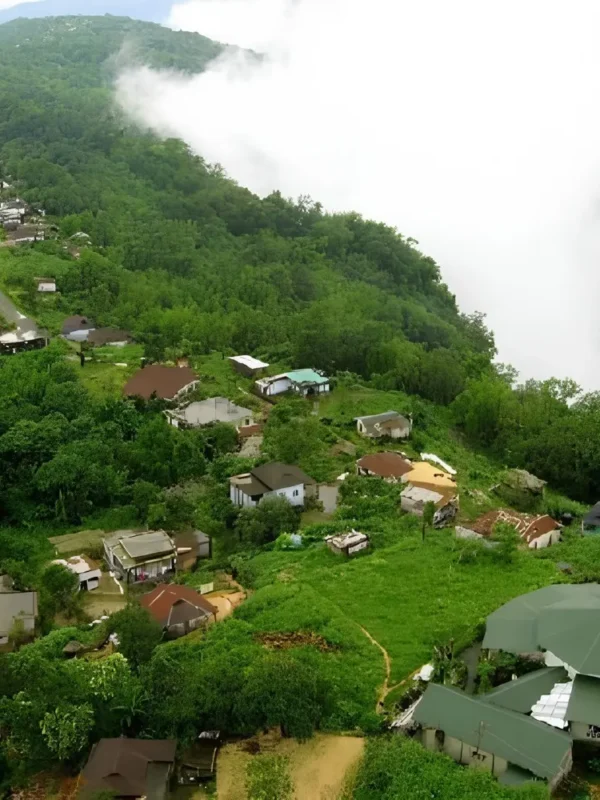 Meghalaya Explorer Package with misty hillside village, lush green forest, valley clouds and scenic Northeast India landscape