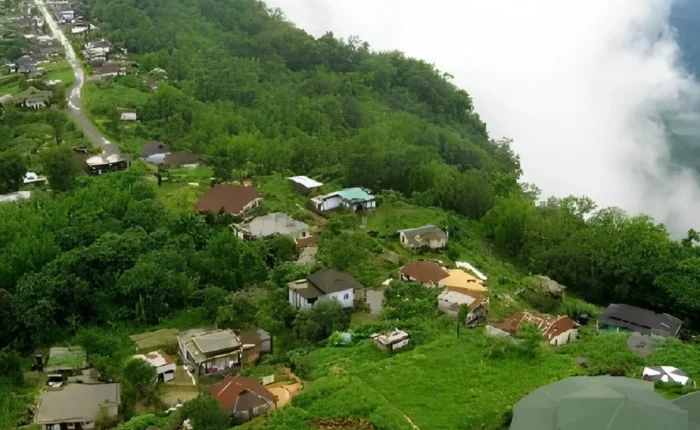 Meghalaya Explorer Package with misty hillside village, lush green forest, valley clouds and scenic Northeast India landscape