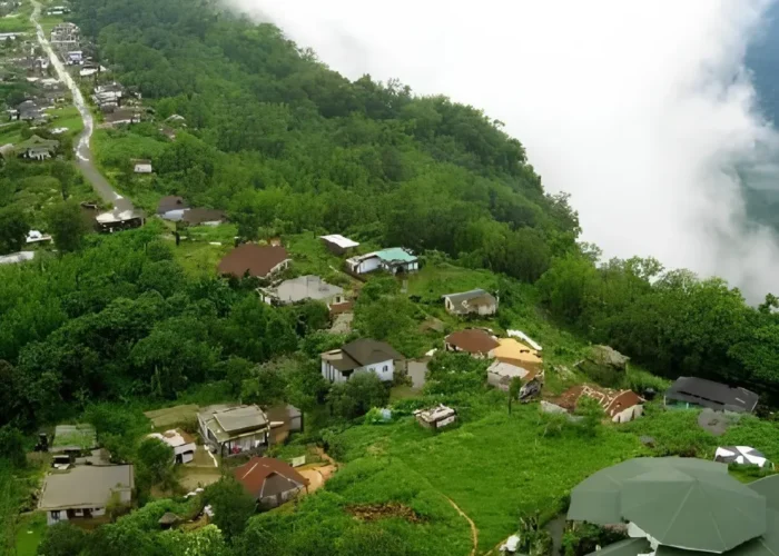 Meghalaya Explorer Package with misty hillside village, lush green forest, valley clouds and scenic Northeast India landscape
