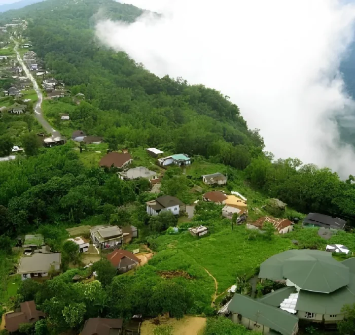 Meghalaya Explorer Package with misty hillside village, lush green forest, valley clouds and scenic Northeast India landscape
