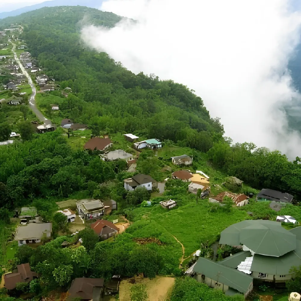 Meghalaya Explorer Package with misty hillside village, lush green forest, valley clouds and scenic Northeast India landscape