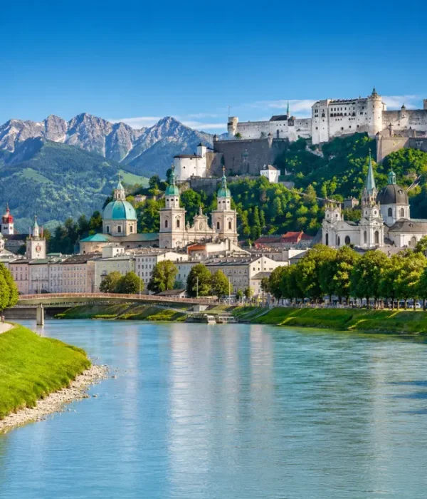 Luxury daytime view of Salzburg, Austria with Hohensalzburg Fortress, Salzach River, churches, and alpine mountains.
