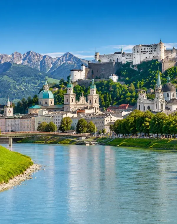 Luxury daytime view of Salzburg, Austria with Hohensalzburg Fortress, Salzach River, churches, and alpine mountains.