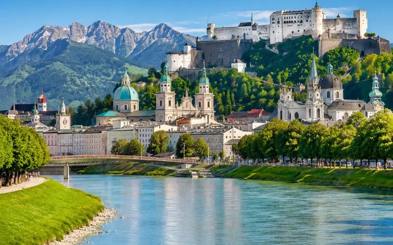Luxury daytime view of Salzburg, Austria with Hohensalzburg Fortress, Salzach River, churches, and alpine mountains.