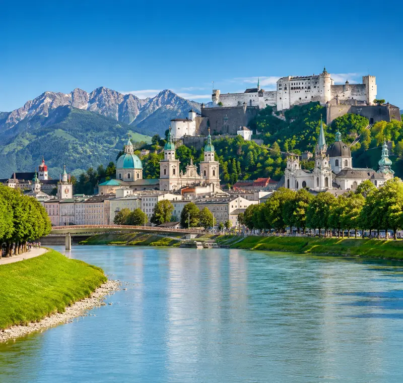 Luxury daytime view of Salzburg, Austria with Hohensalzburg Fortress, Salzach River, churches, and alpine mountains.