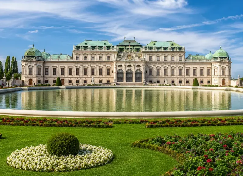 Luxury daytime view of Vienna’s Belvedere Palace with formal gardens, reflecting pool, and elegant Baroque architecture.