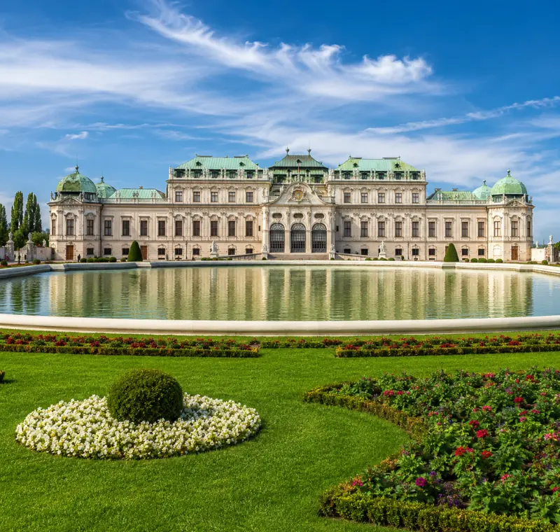 Luxury daytime view of Vienna’s Belvedere Palace with formal gardens, reflecting pool, and elegant Baroque architecture.