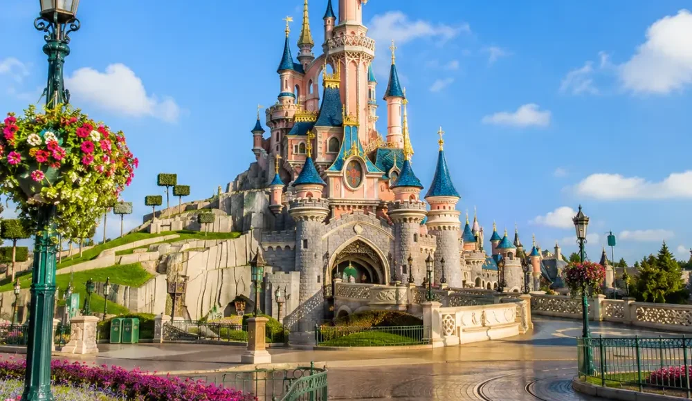Disneyland Paris castle with fantasy gardens, clean pathways, blue sky, and bright morning family travel atmosphere